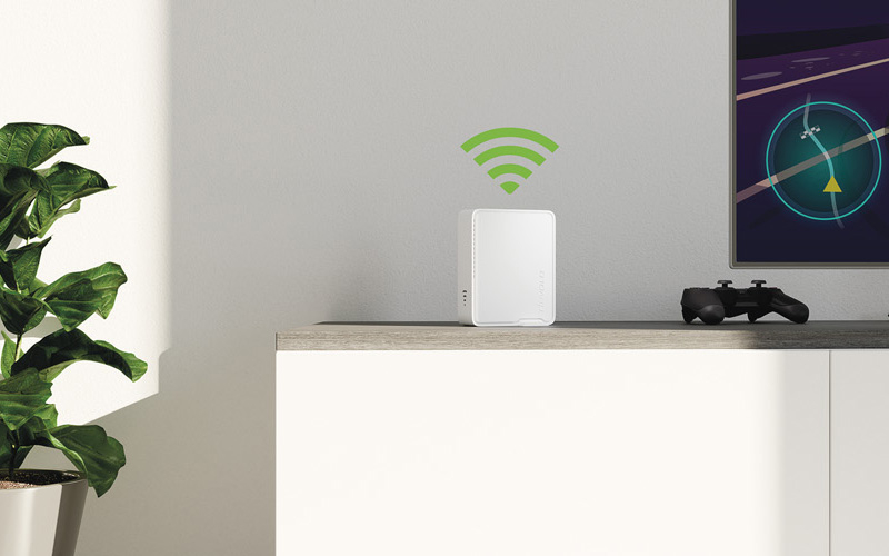 Ein Repeater von devolo steht auf einer TV-Bank im Wohnzimmer.
