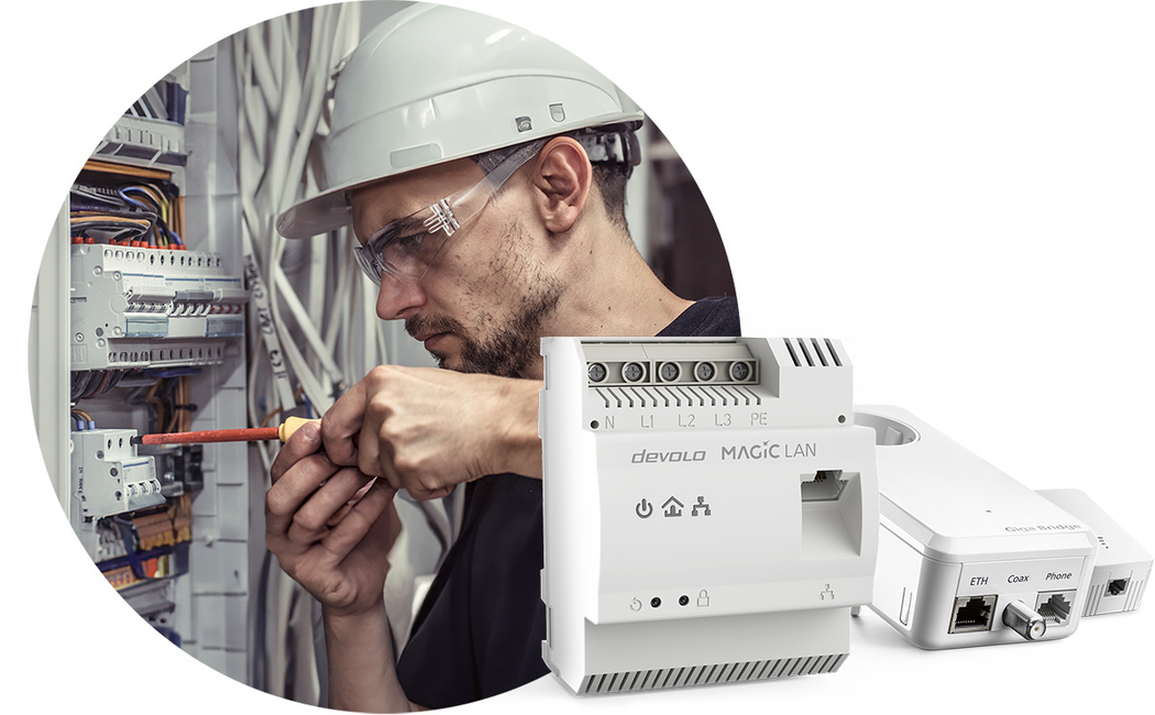 Ein Elektriker schraubt an einem Schaltschrank, vor ihm aufgereiht sind mehrere devolo-Produkte.