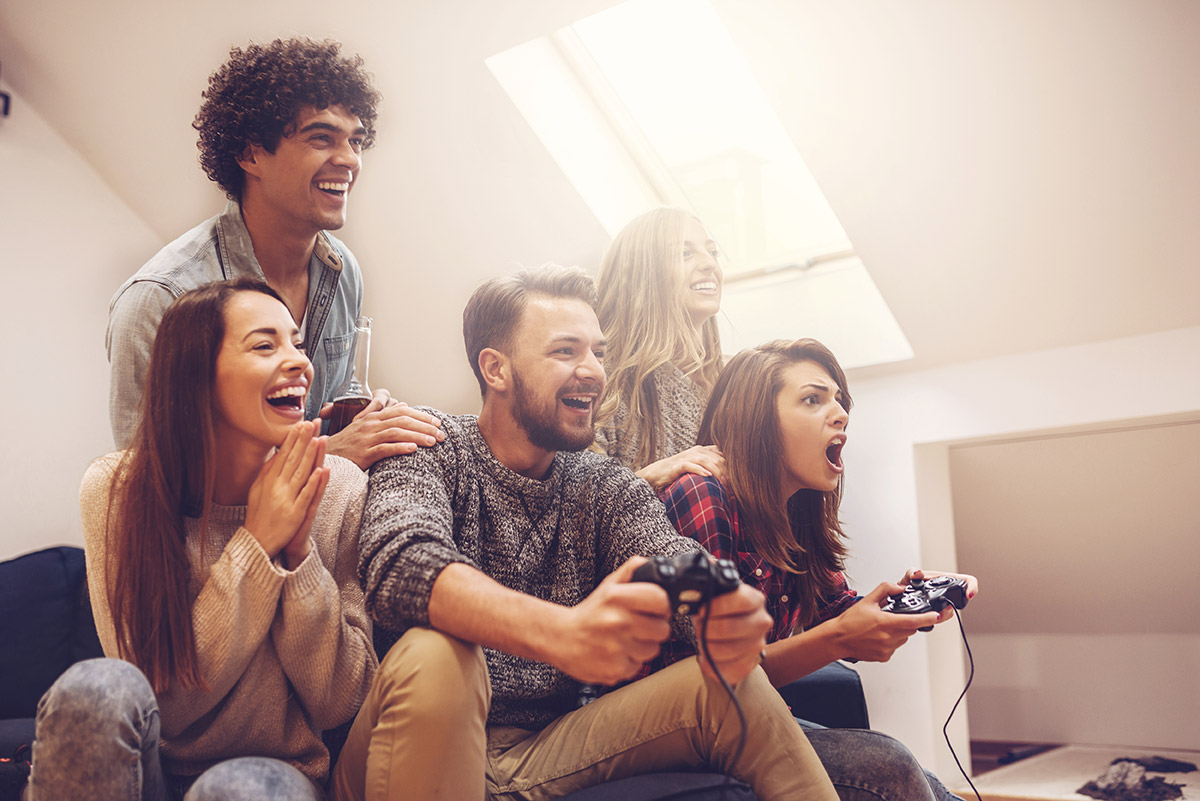 Fünf Freunde mit Konsolen in der Hand die gamen