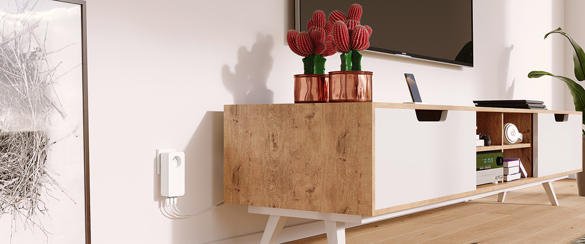 A côté d'une armoire dans le salon, un devolo dLAN 1200 plus WiFi ac est branché dans une prise murale. Trois câbles LAN sont reliés à l'adaptateur CPL.