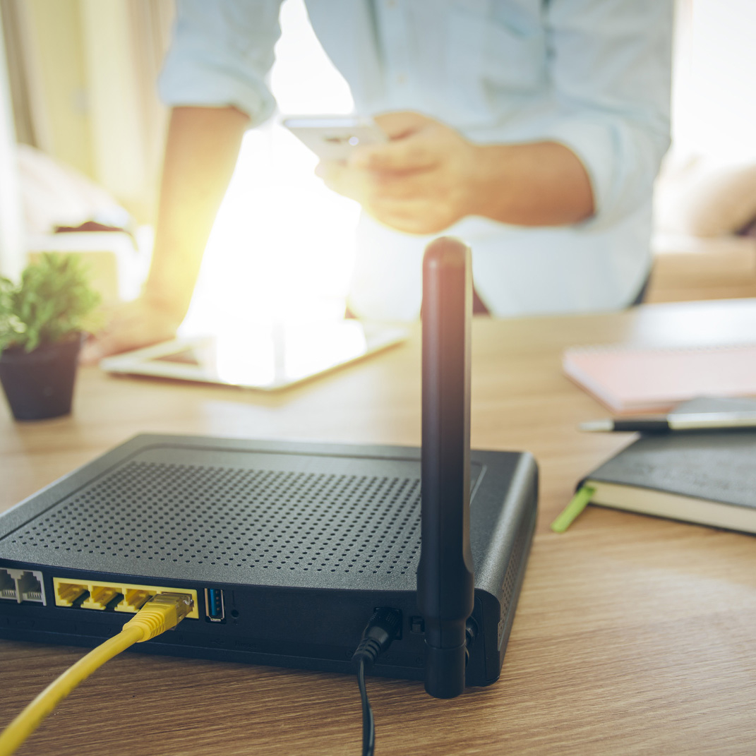 Ein Router auf einem Tisch. Smartphones und weitere Endgeräte werden mit WLAN versorgt.