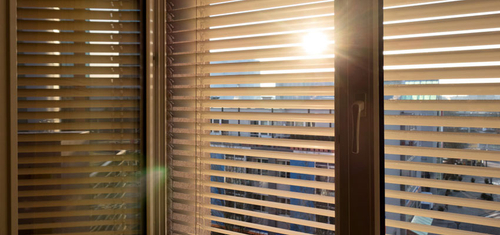 Ein Fenster mit Rolladen und die Sonne scheint dadurch