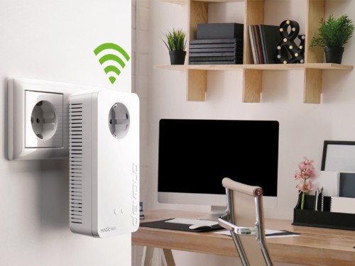 A devolo Magic 2 WiFi 6 powerline adapter with WiFi waves is plugged into a socket in the home office.