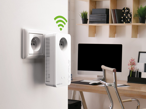 Un adaptateur CPL devolo Magic 2 WiFi 6 avec ondes WiFi est branché sur une prise dans un bureau à domicile.